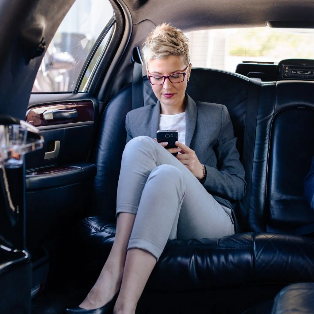 Professional businesswoman working comfortably inside a luxury sedan, highlighting the executive Bracebridge Limo Service for corporate and secure business travel.