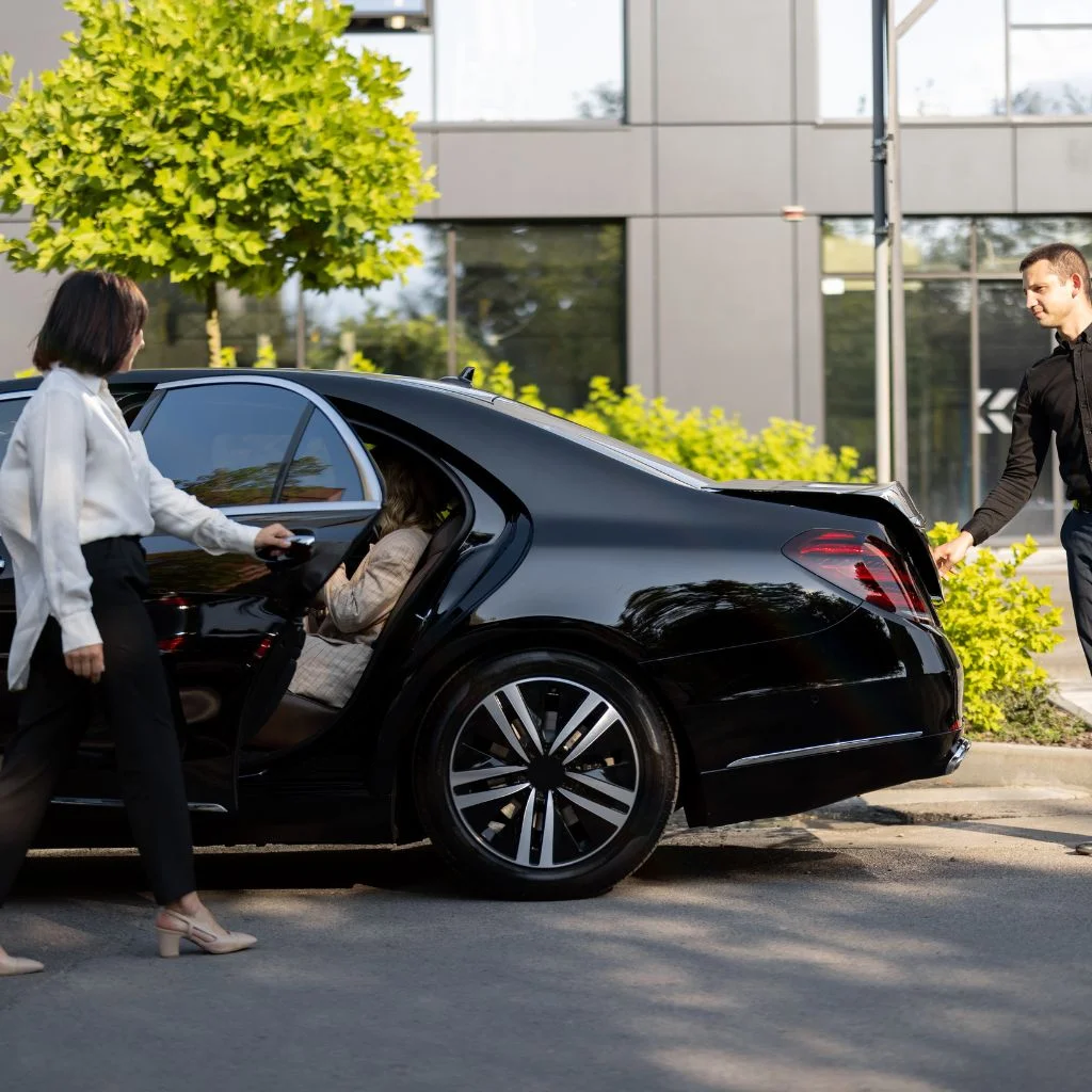 Executive black luxury sedan demonstrating premium Gravenhurst Limo Service, with a chauffeur assisting a client upon arrival at a corporate or upscale destination.